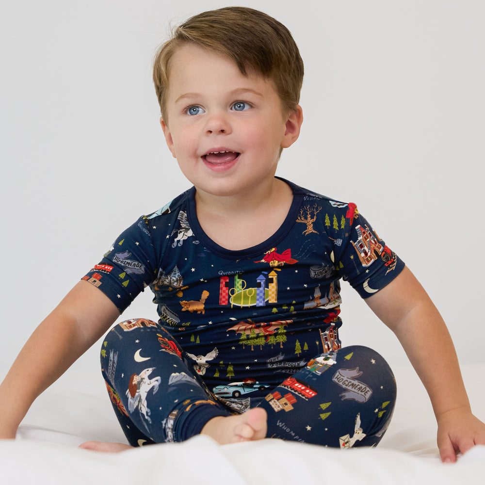 Child sitting on a bed wearing An Evening at Hogwarts two piece short sleeve pj set