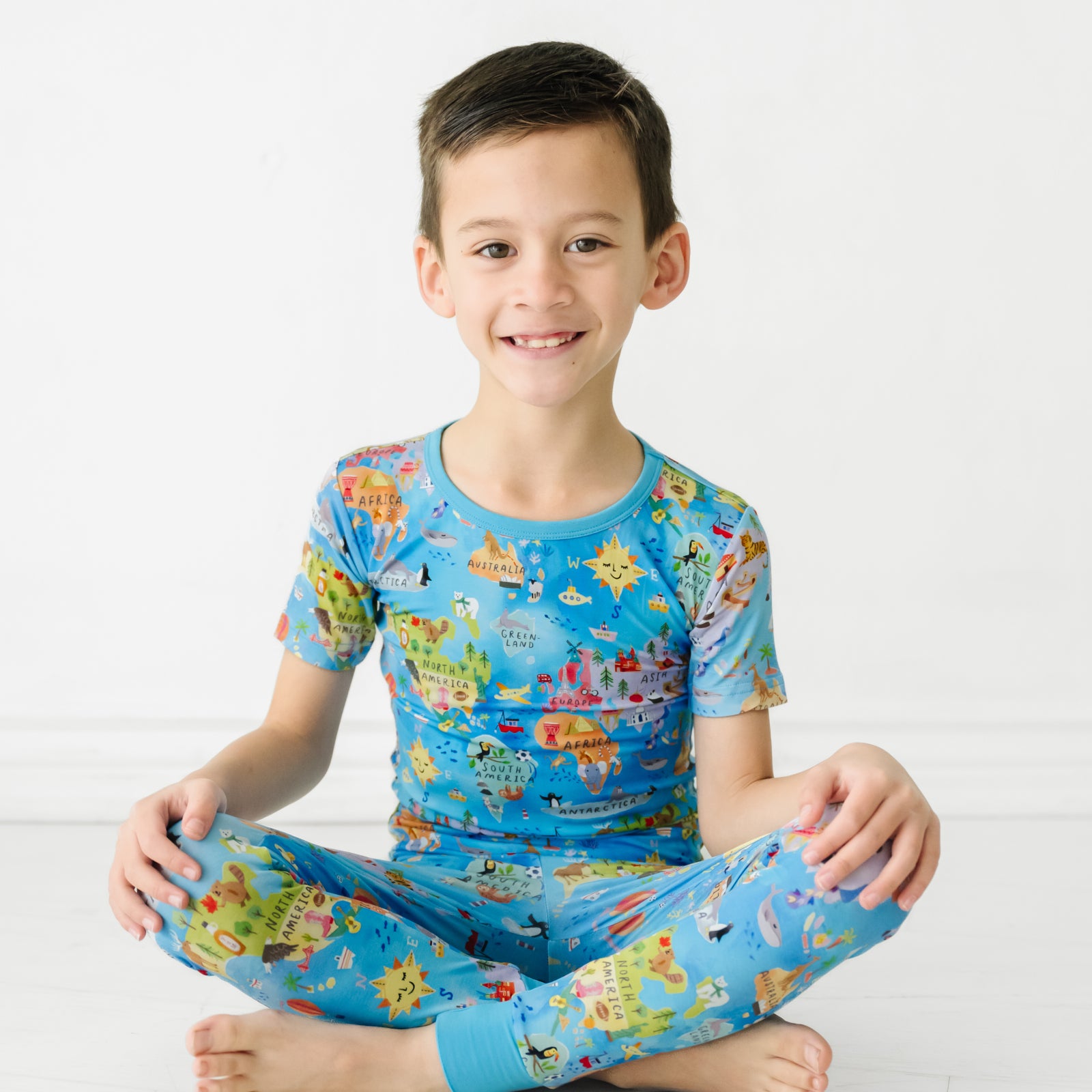 Child sitting wearing an Around the World two piece short sleeve pajama set