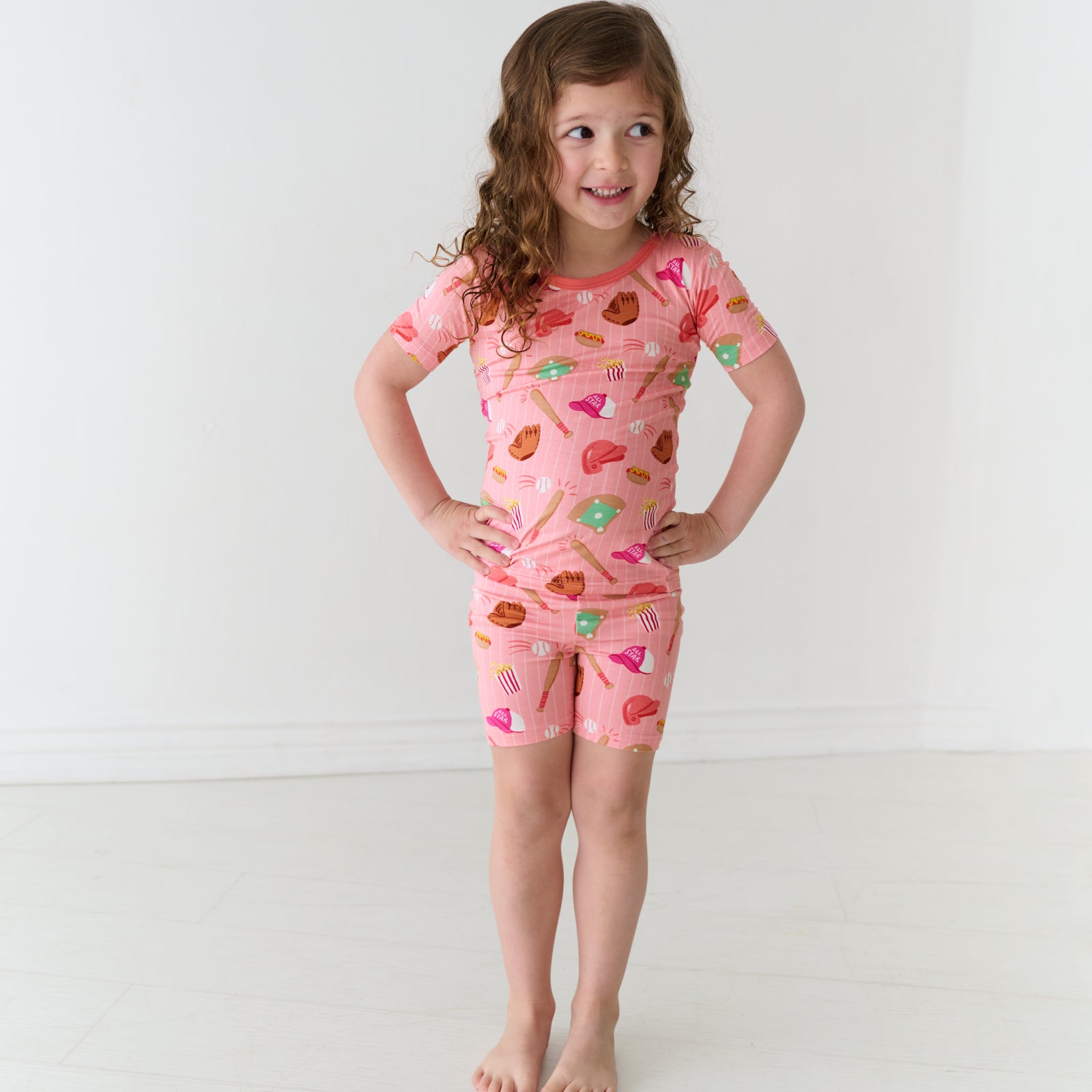 Child posing wearing Pink All Stars two piece short sleeve and shorts pajama set