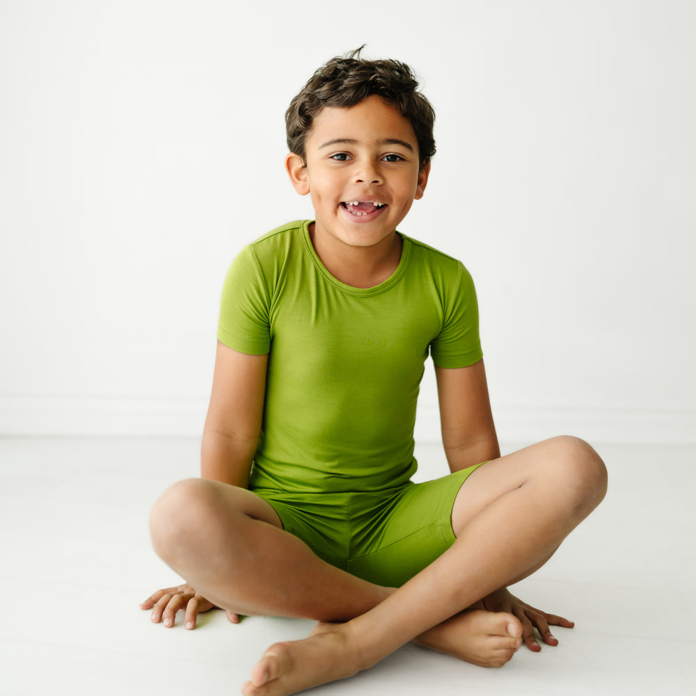 Child sitting wearing an Avocado two piece short sleeve and shorts pajama set