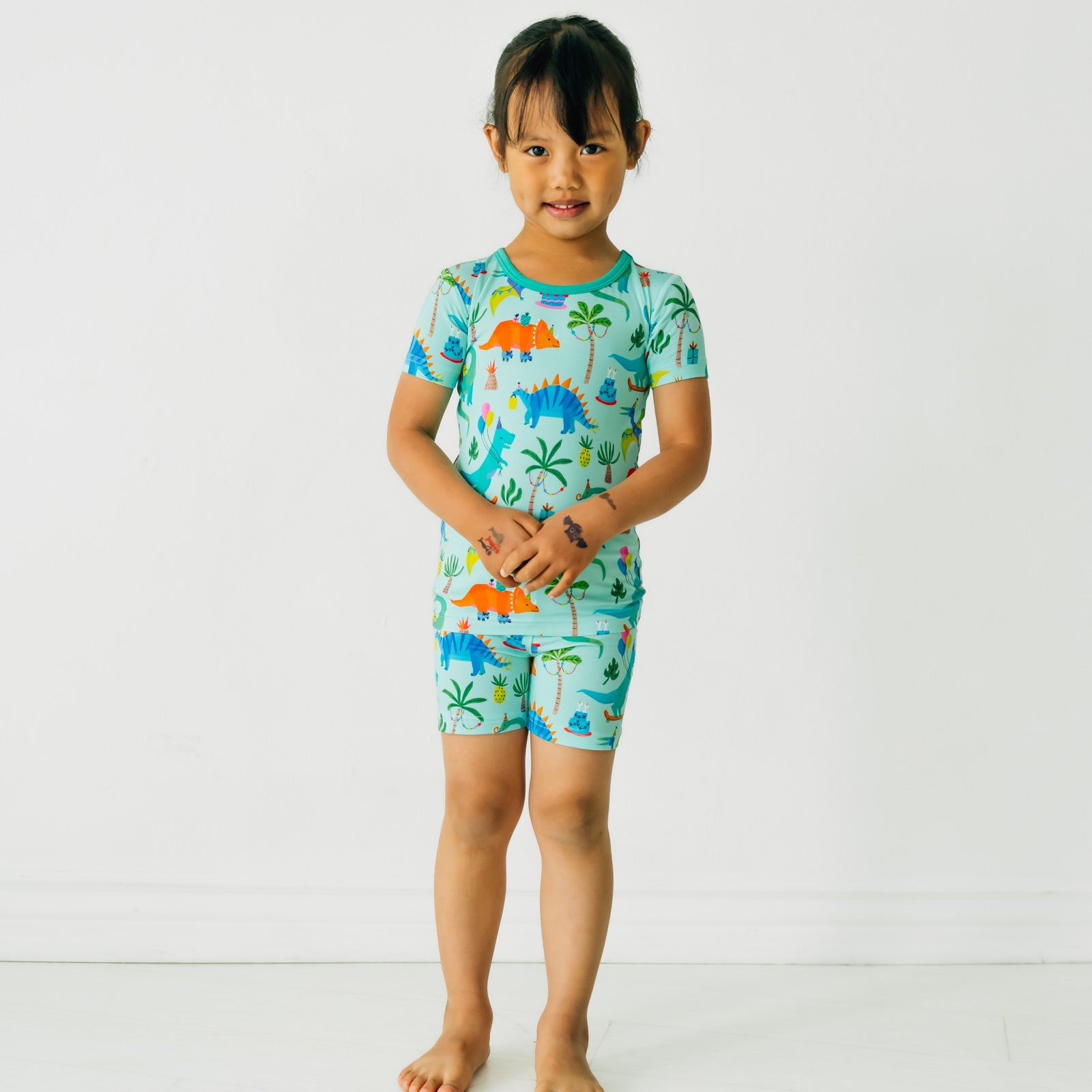 child posing wearing Prehistoric Party two piece short sleeve and shorts pj set