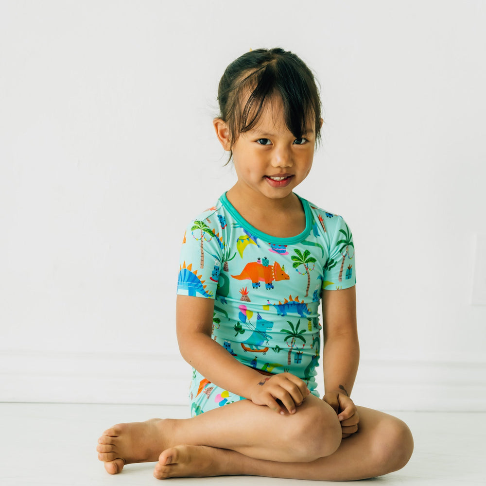 child sitting wearing Prehistoric Party two piece short sleeve and shorts pj set