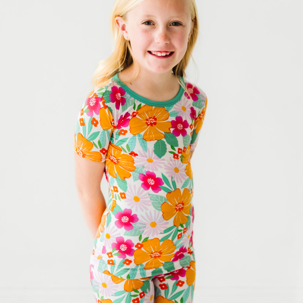 Close up image of a child posing wearing Beachy Blooms two piece short sleeve and shorts pajama set