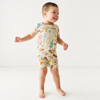 child playing wearing a Caramel Ready to Rodeo two piece short sleeve and shorts pajama sets