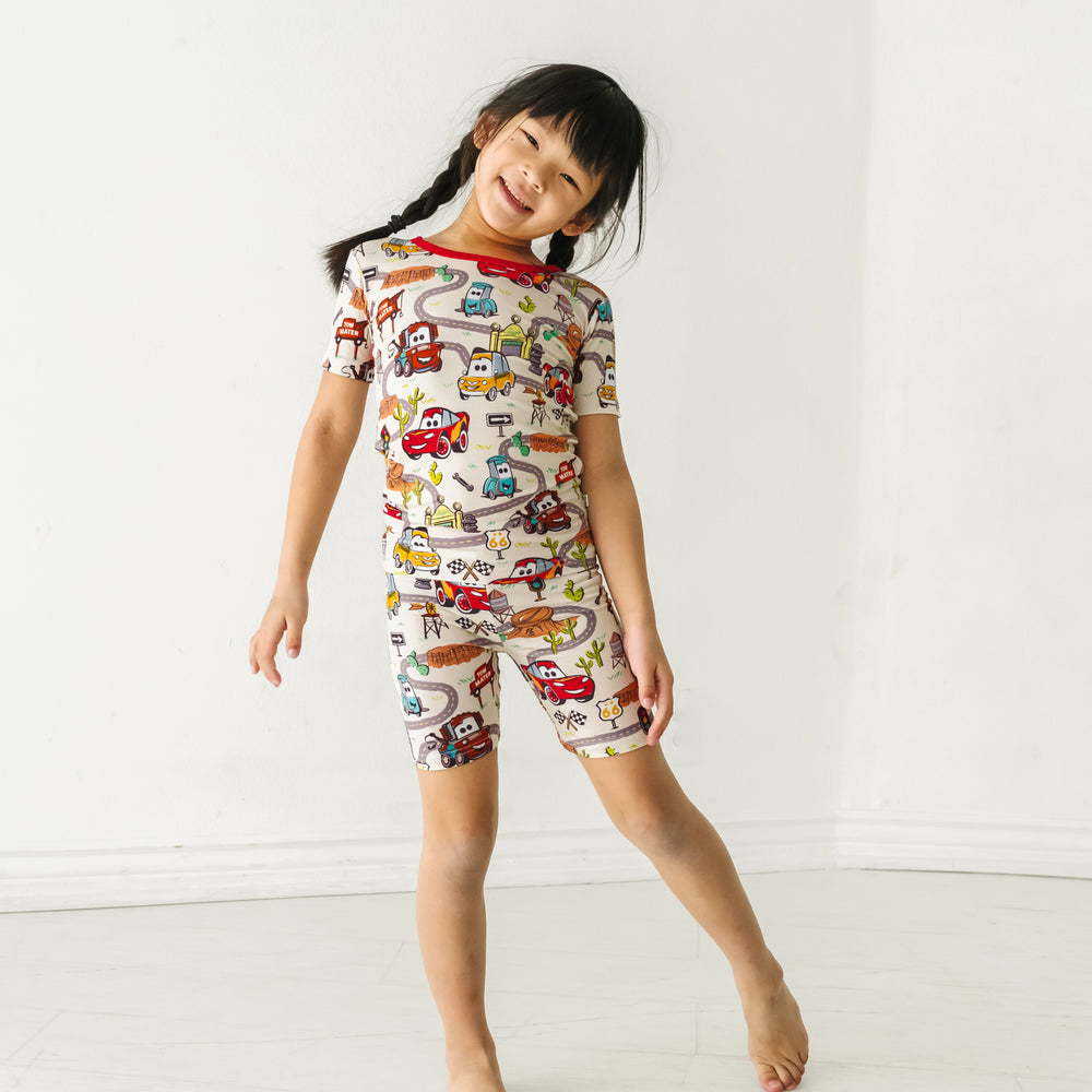 Child posing wearing a Radiator Springs two piece short sleeve and shorts pajama set