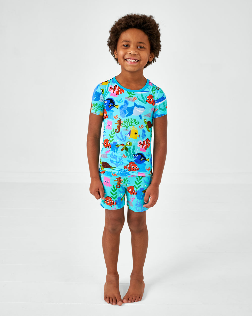 Standing child wearing the Disney Nemo's Reef Two-Piece Short Sleeve & Shorts Pajama Set