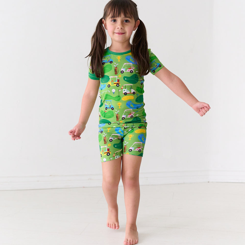 Child wearing a Fairway Fun two-piece short sleeve and shorts pajama set