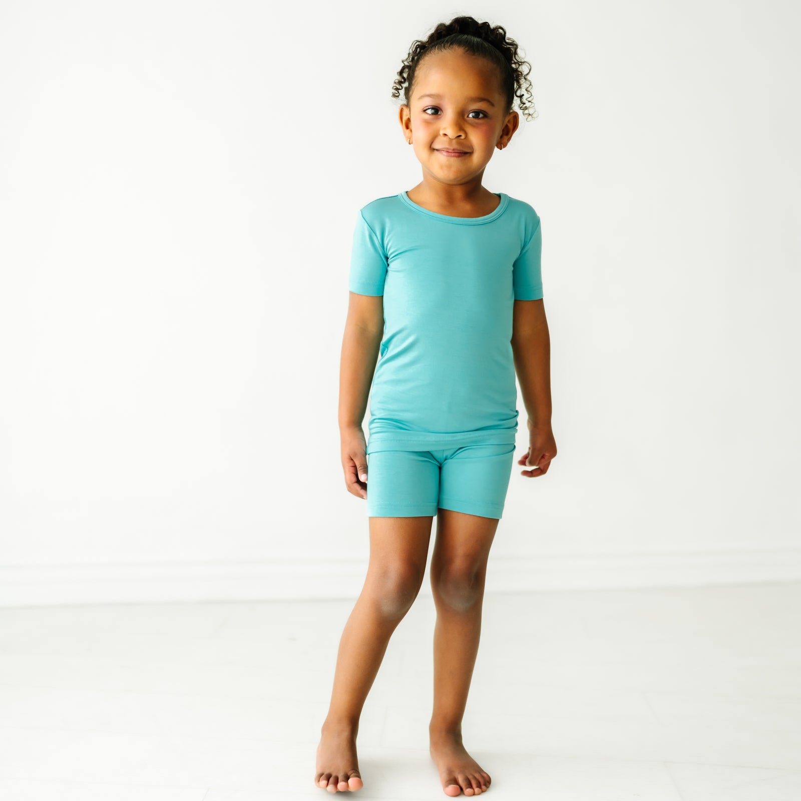 Child wearing a Glacier Turquoise two piece short sleeve and shorts pajama set