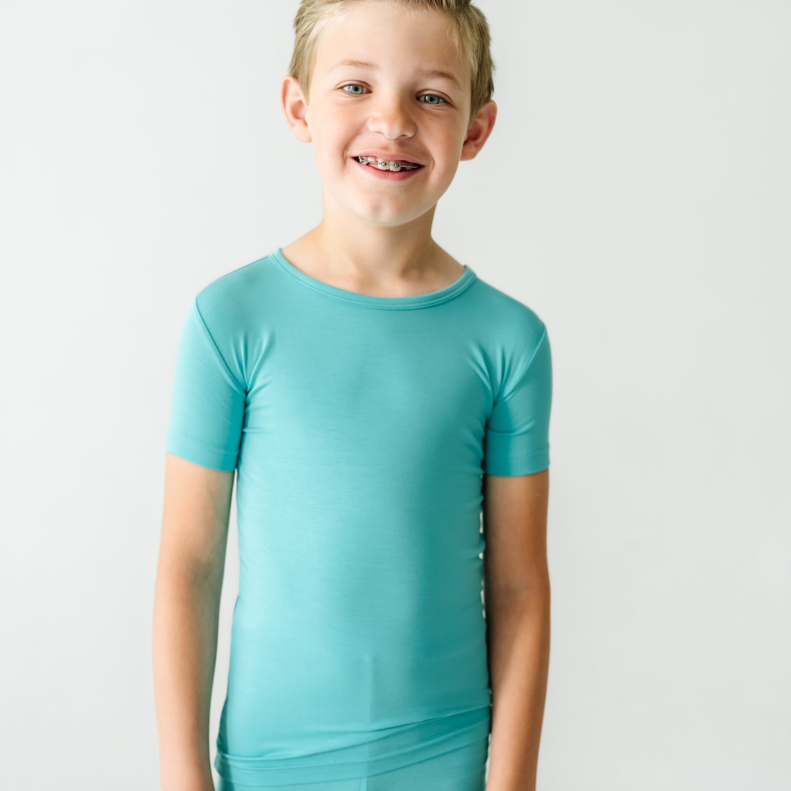 Close up image of a child wearing a Glacier Turquoise two piece short sleeve and shorts pajama set