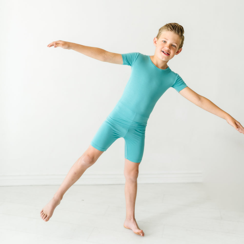 Child posing wearing Glacier Turquoise two piece short sleeve and shorts pajama set