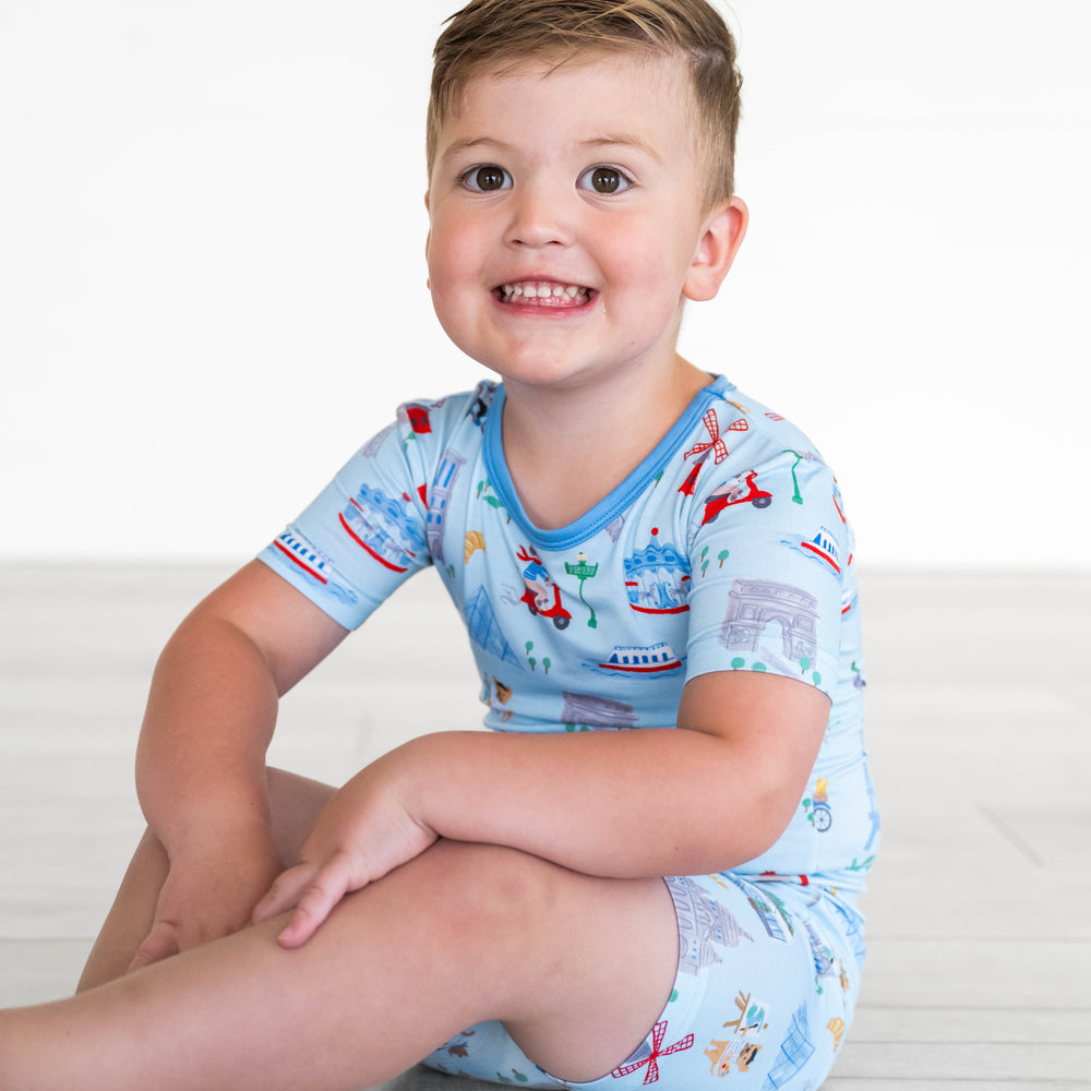 Boy sitting while wearing the Blue Weekend in Paris Two-Piece Short Sleeve & Shorts Pajama Set