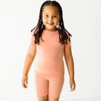 Child wearing a Peach two piece short sleeve and shorts pajama set