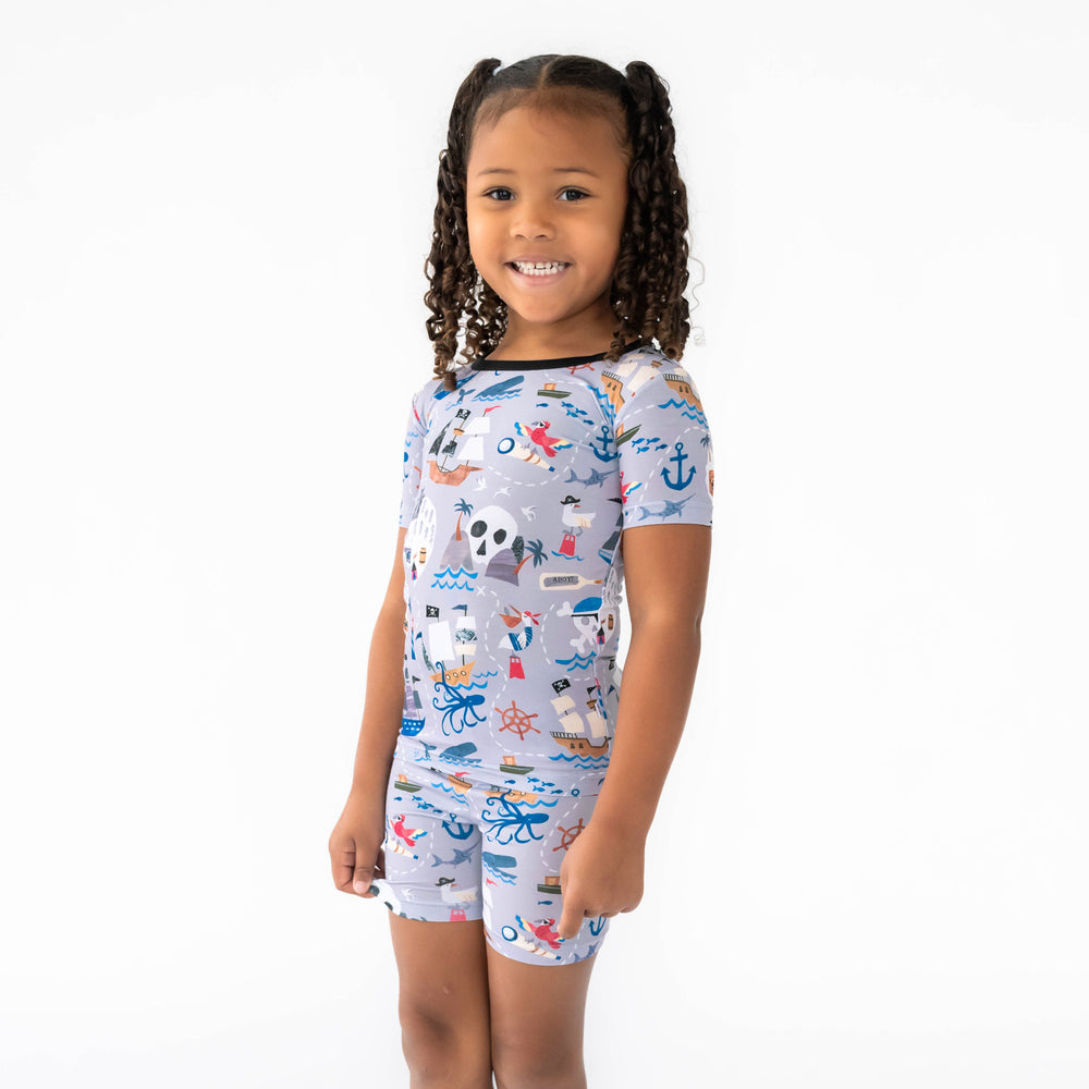 Girl standing to the side while wearing the Pirate's Map Two-Piece Short Sleeve & Shorts Pajama Set