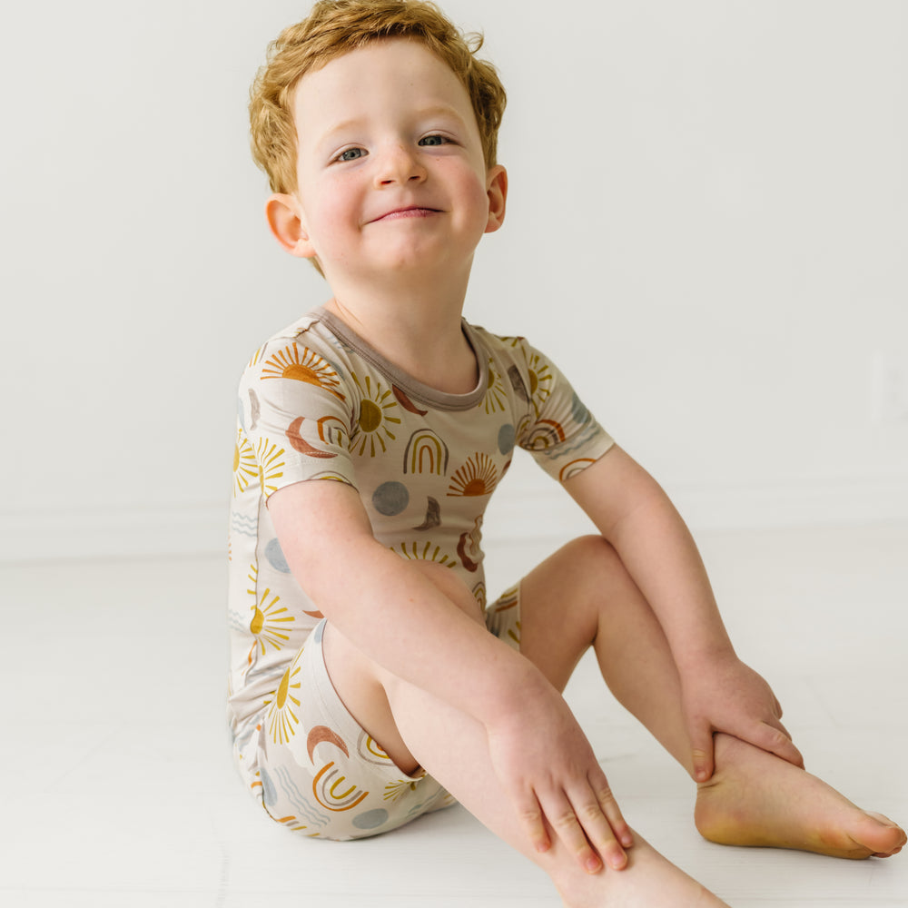 Child sitting wearing a Desert Sunrise two piece short sleeve and shorts pajama set