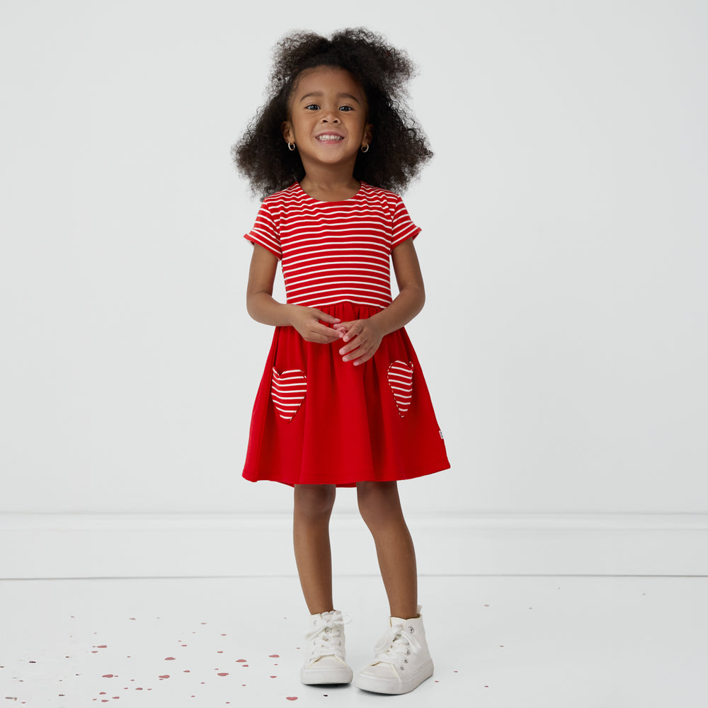 Smiling child wearing a Candy Red Patch Pocket Dress