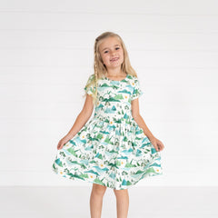 Image of a child wearing a Mountain Mist Patch Pocket Dress, holding out the sides of the dress