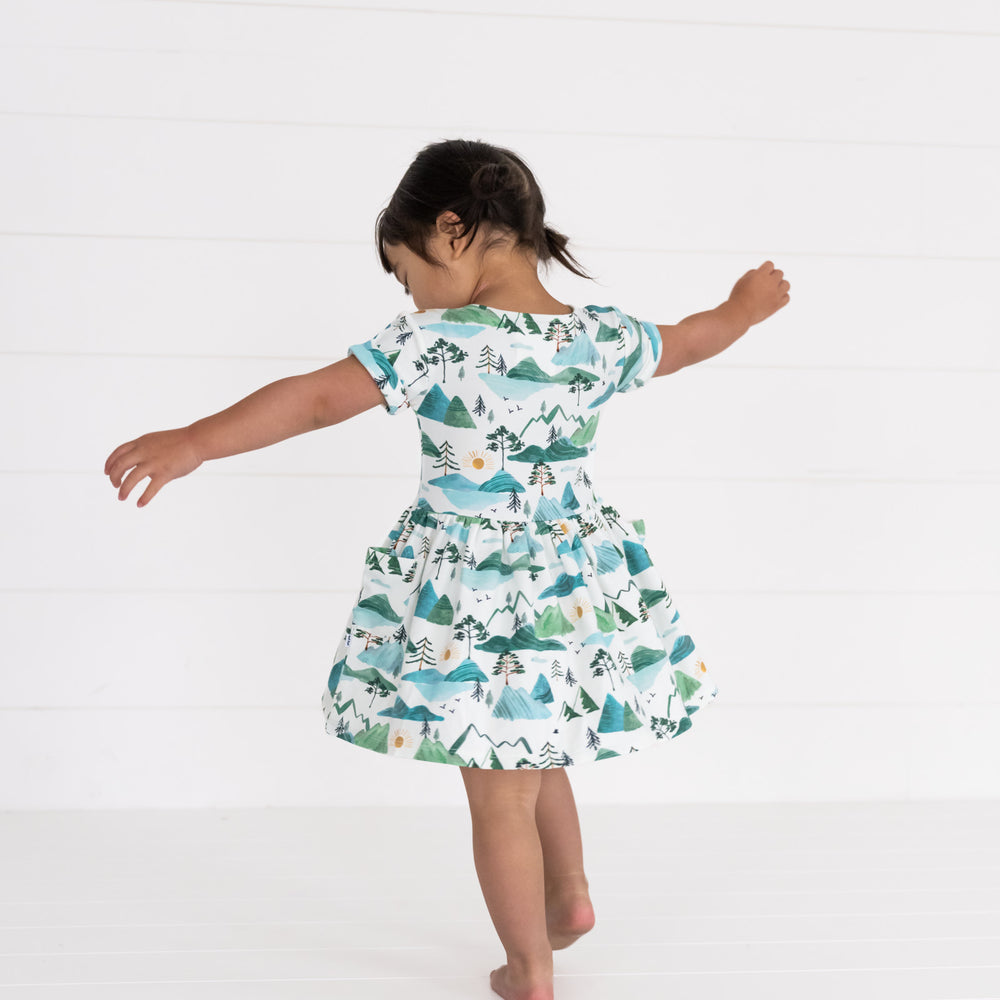 Image of a child spinning around wearing a Mountain Mist Patch Pocket Dress with Bloomer