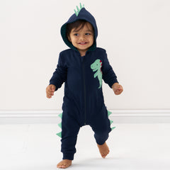 Child wearing a Dinosaur sweatsuit romper with the hood up