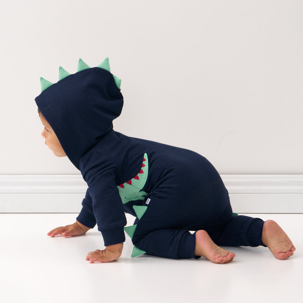 Click to see full screen - Side view image of a child crawling on the ground wearing a Dinosaur sweatsuit romper with the hood up
