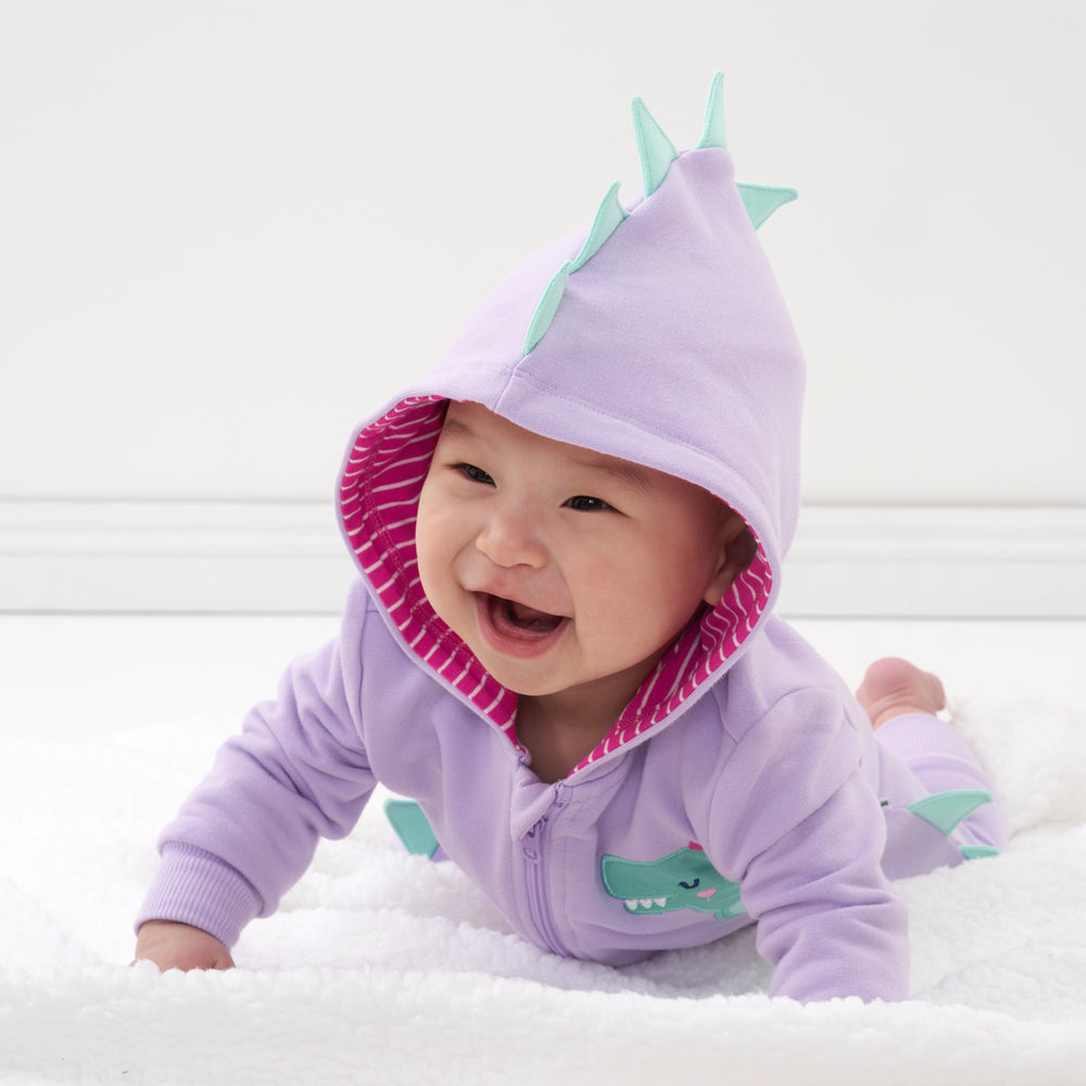 Click to see full screen - Child crawling on a blanket wearing a Loveasaurus sweatsuit romper with the hood up