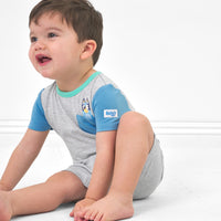 Child sitting on the ground wearing a Bluey graphic pocket shorty romper