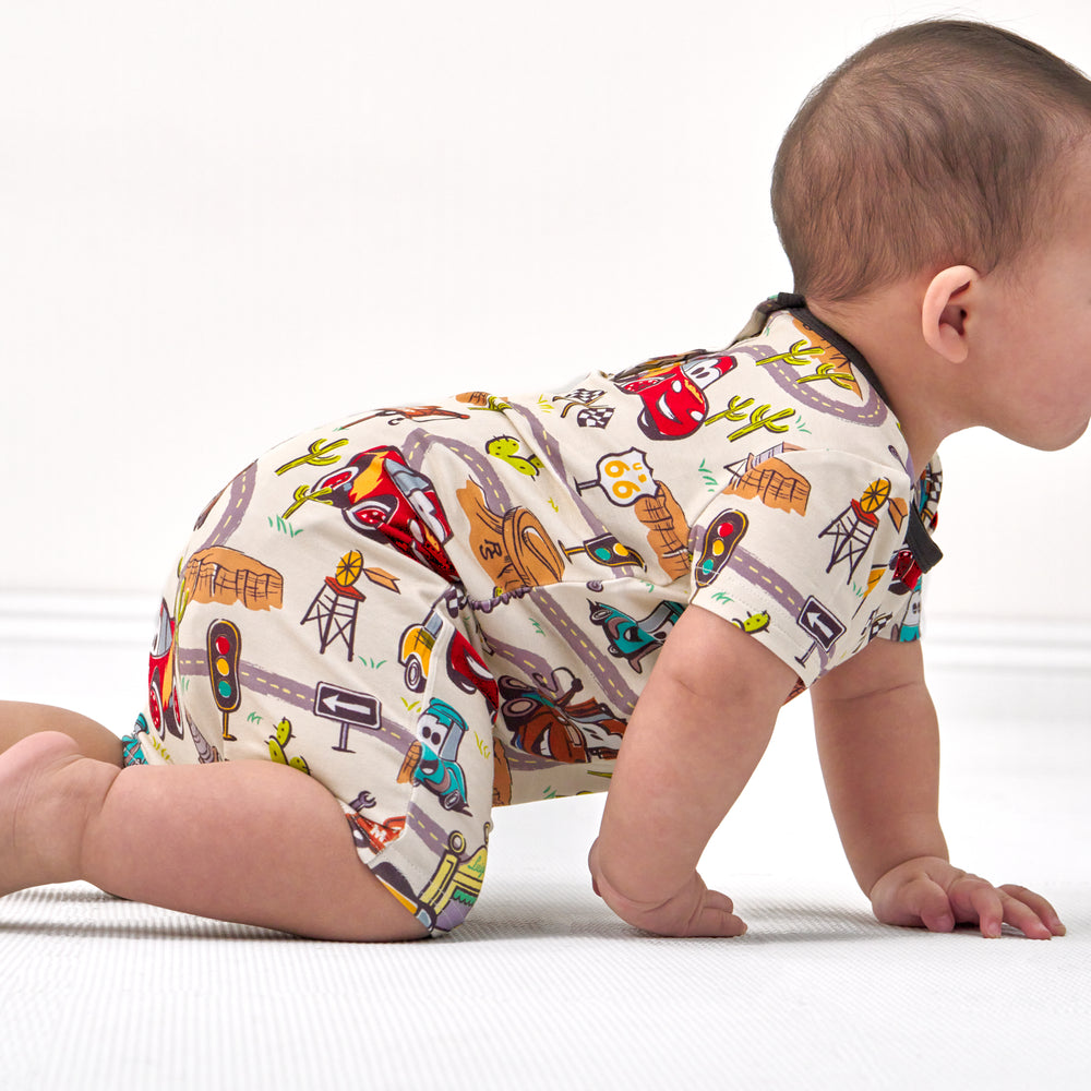 Side view image of a child crawling on the ground wearing a Radiator Springs pocket shorty romper