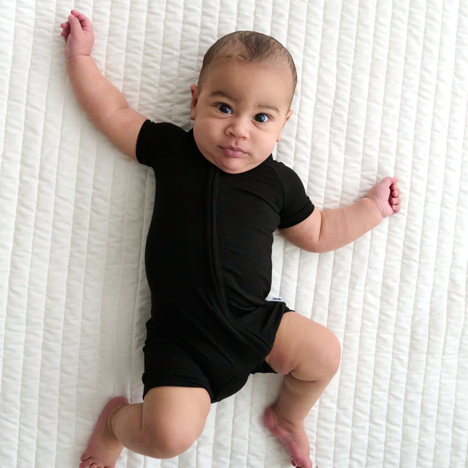 Child laying on a bed wearing a solid Black shorty zippy