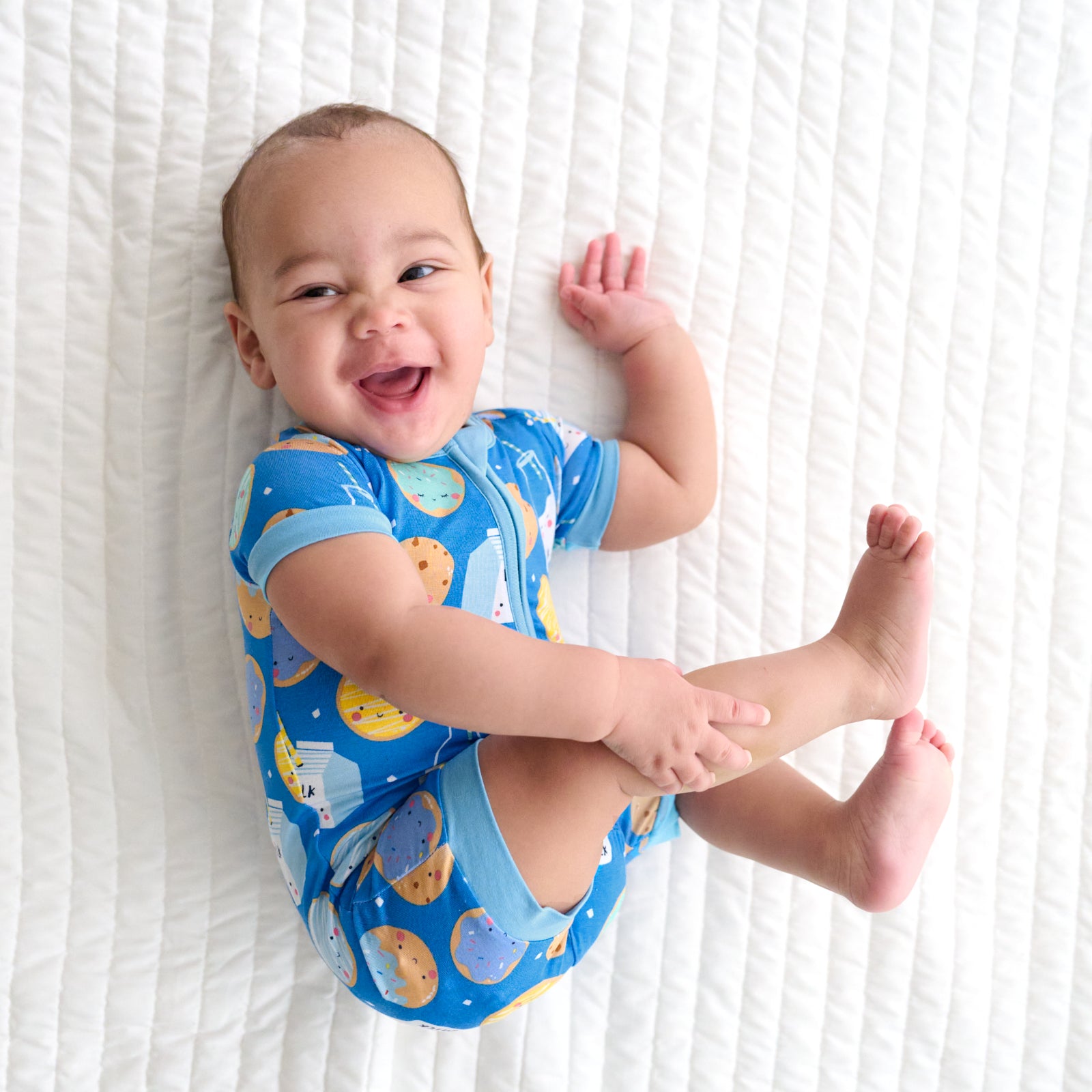 Child laying on a bed wearing a Blue Cookies & Milk Shorty Zippy