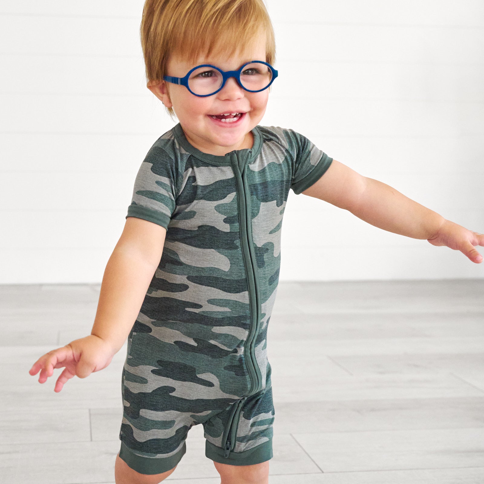 Boy in glasses smilling while wearing the Vintage Camo Shorty Zippy