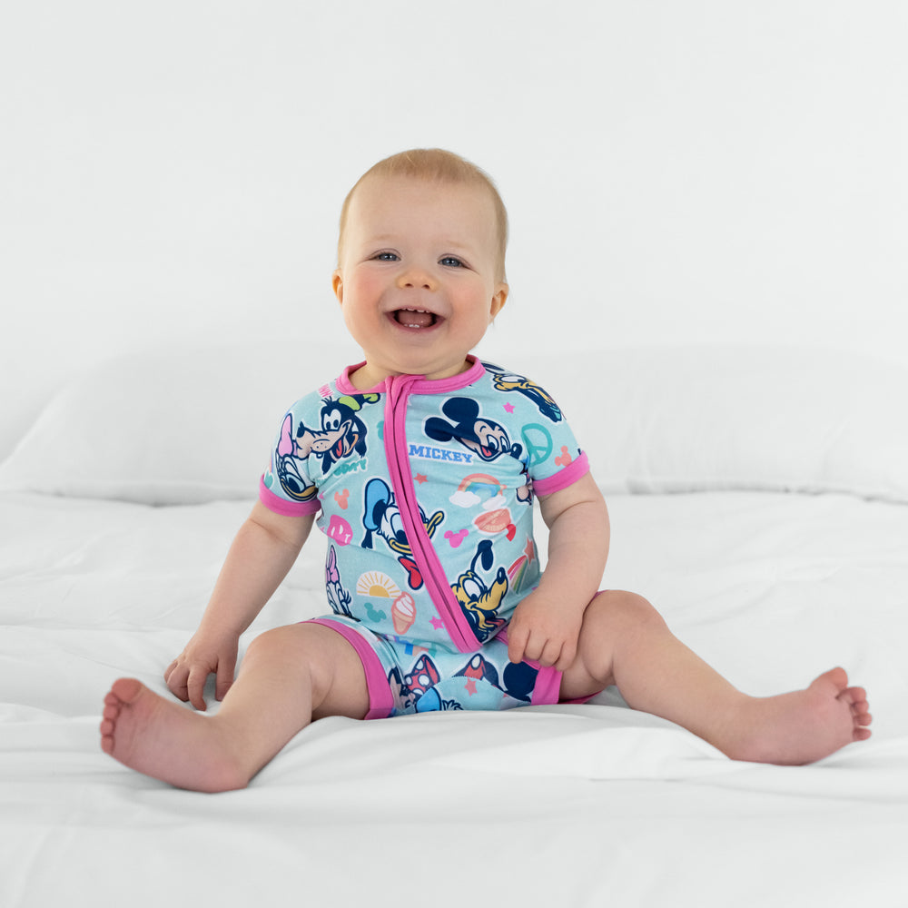 Child sitting on a bed wearing Pink Disney Mickey's Clubhouse bamboo baby pajamas