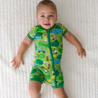 Child laying on a blanket wearing a Fairway Fun shorty zippy
