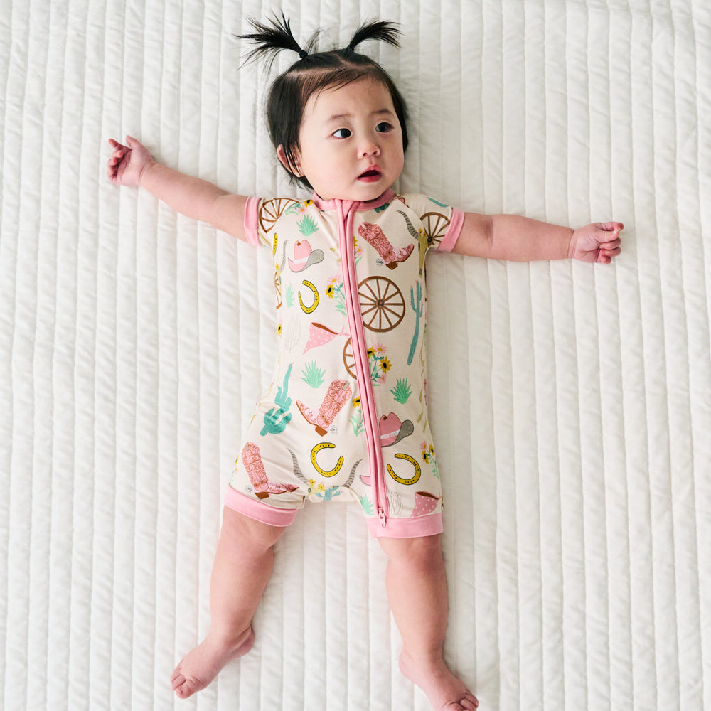 Child laying on a bed wearing a Pink Ready to Rodeo Shorty Zippy