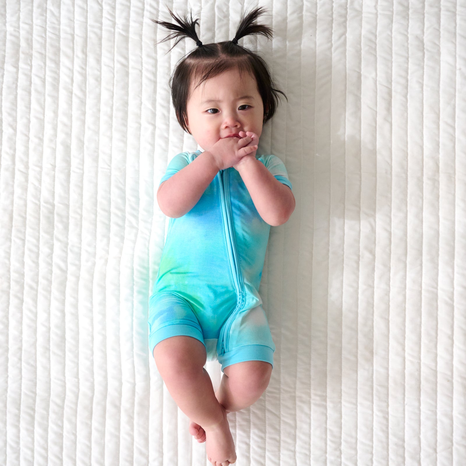 Child laying on a bed wearing a Tidepool Watercolor Shorty Zippy