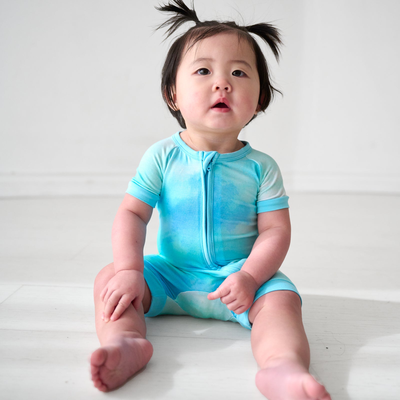 Child sitting wearing a Tidepool Watercolor Shorty Zippy