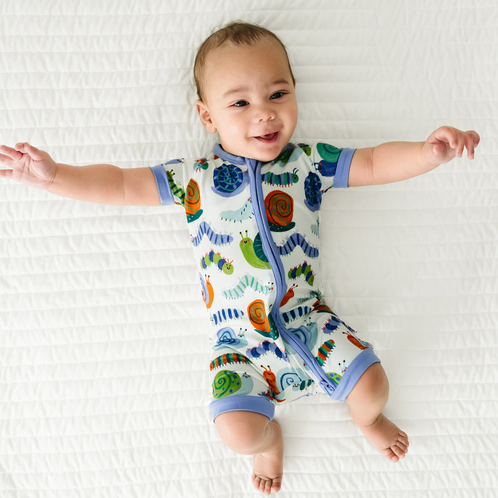 Child laying on a blanket wearing an Inchin' Along shorty zippy