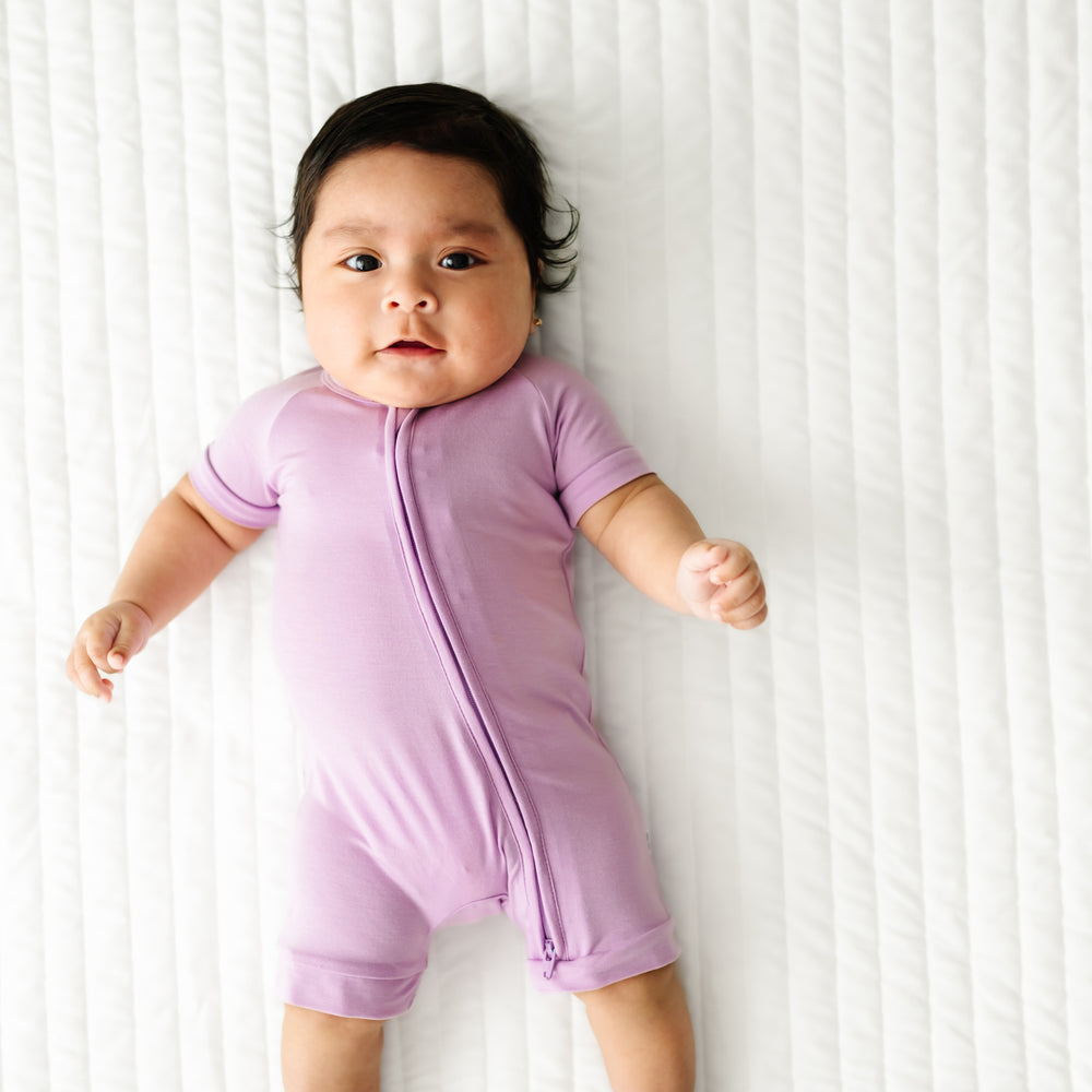 Child laying on a bed wearing a Light Orchid shorty zippy