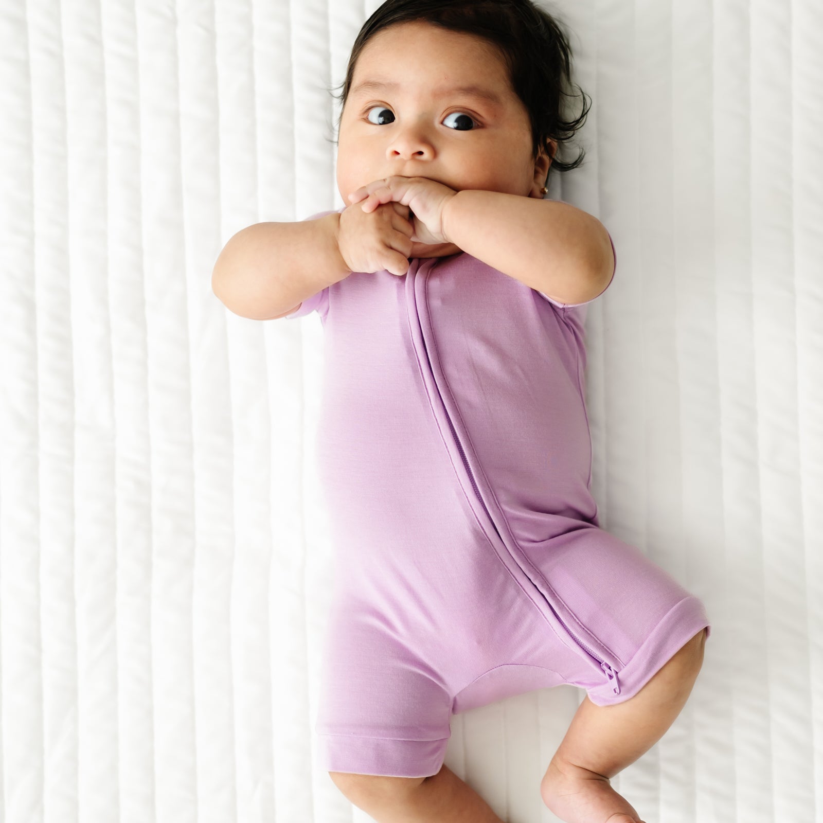 Alternate image of a child laying on a bed wearing a Light Orchid shorty zippy