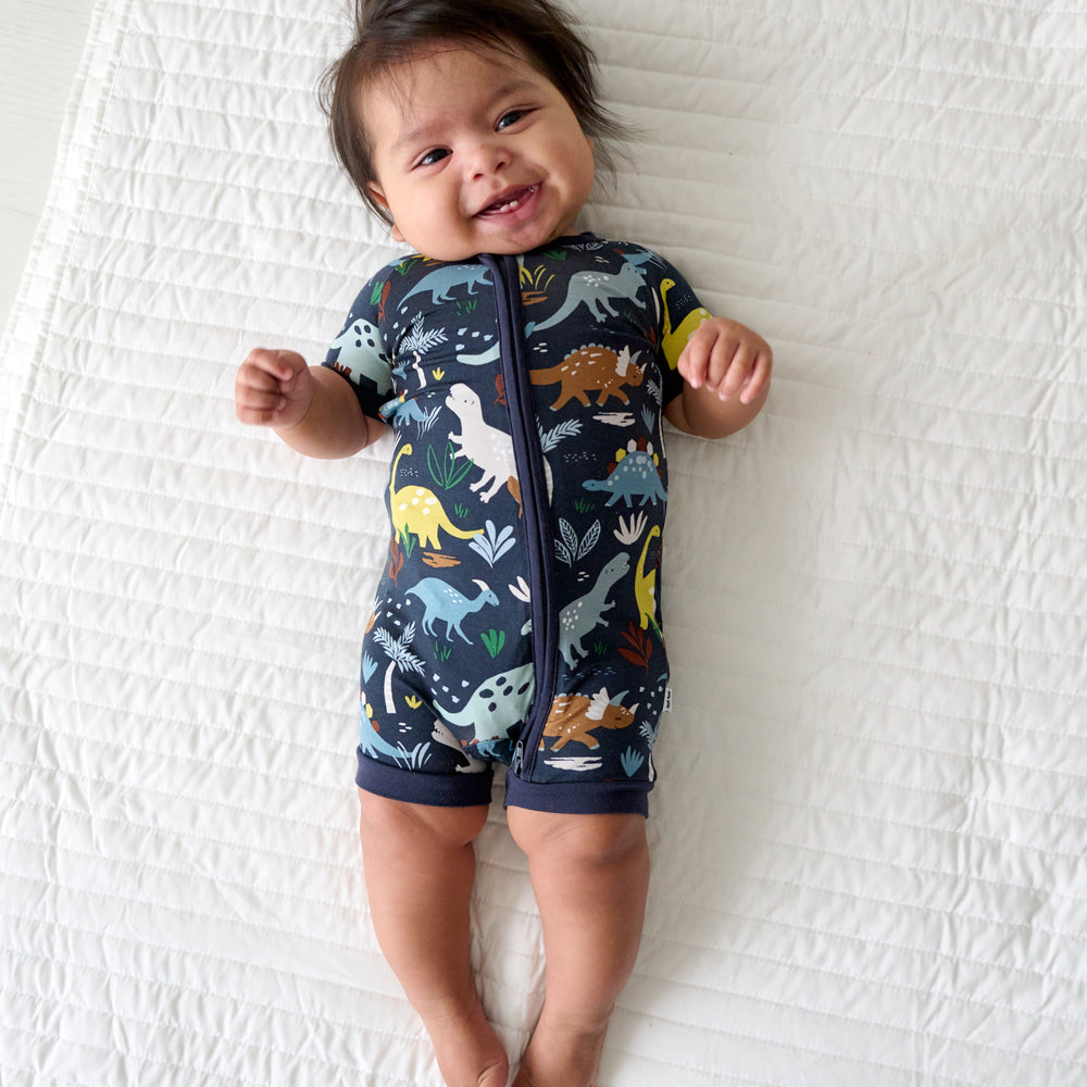 Child laying on a bed wearing a Navy Jurassic Jungle Shorty Zippy