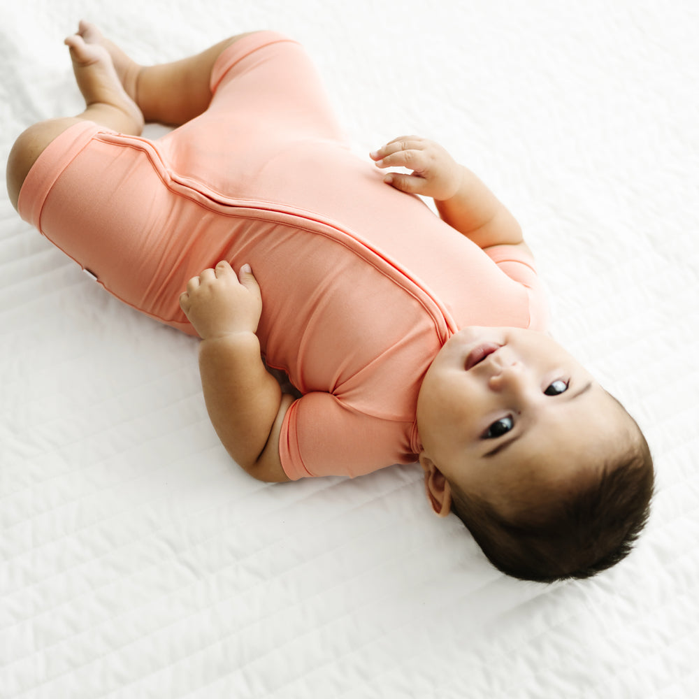 Alternate image of a child laying on a bed wearing a Peach shorty zippy