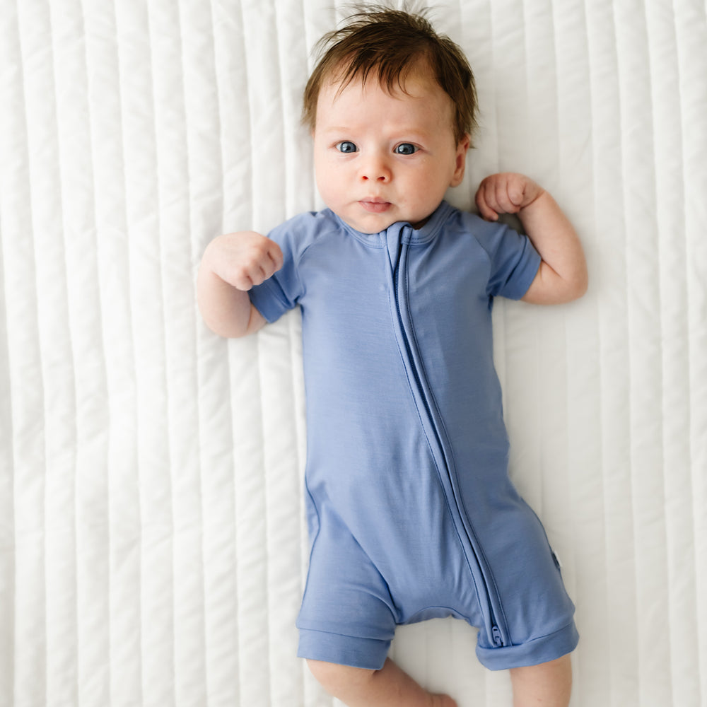 Child laying on a bed wearing a Slate Blue shorty zippy