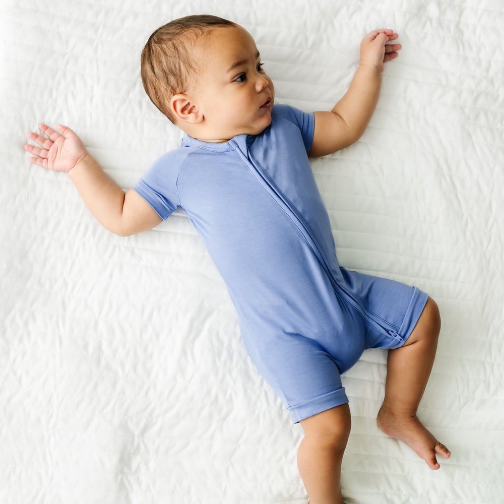 Alternte image of a child laying on a bed wearing a Slate Blue shorty zippy