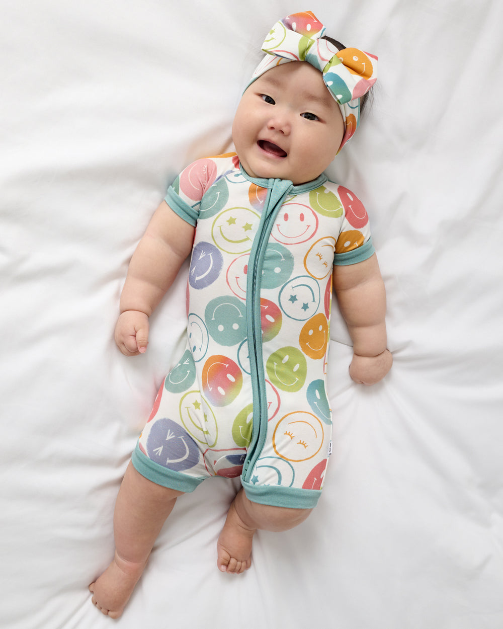 Aerial view of baby wearing the Positive Vibes Shorty Zippy and Luxe Bow Headband