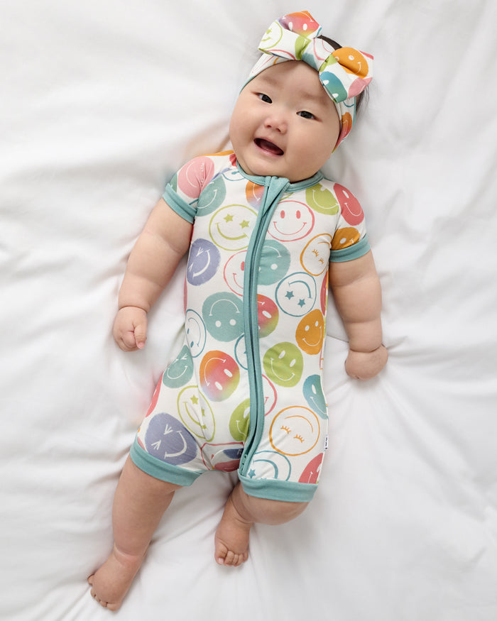 Aerial view of baby wearing the Positive Vibes Shorty Zippy and Luxe Bow Headband