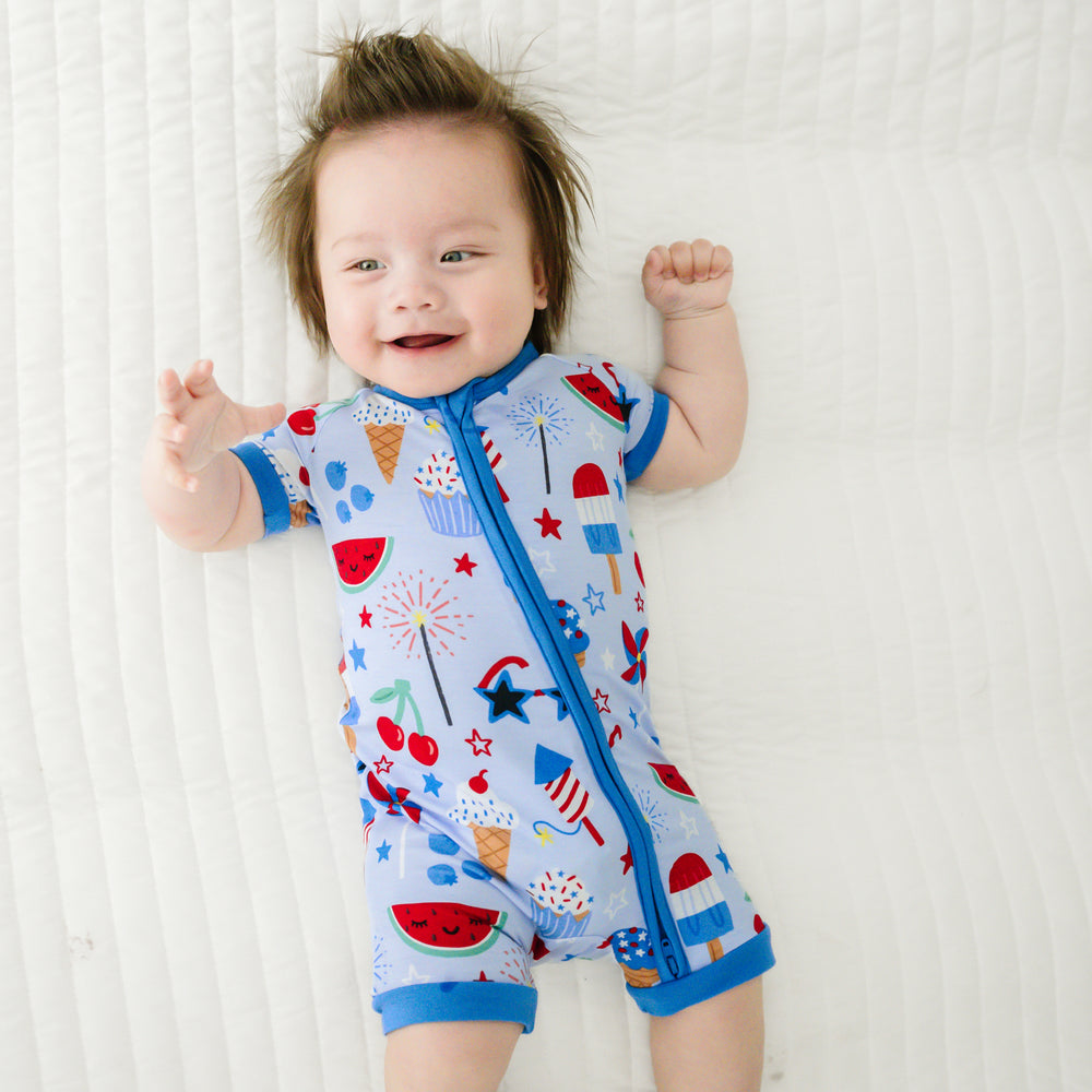 Child laying on a bed wearing a Stars, Stripes, and Sweets shorty zippy