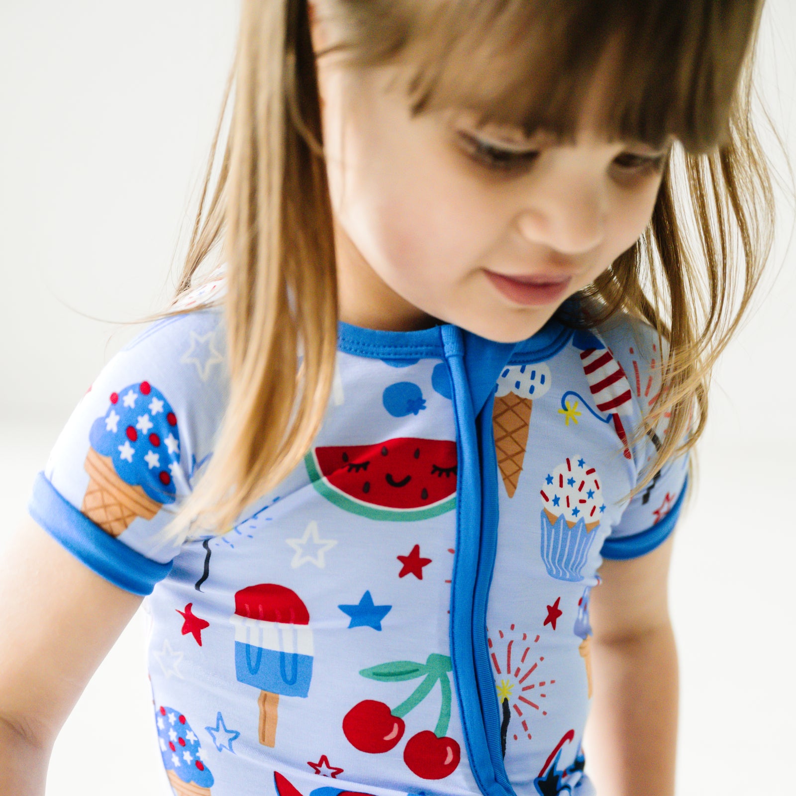 Close up image of a child wearing a Stars, Stripes, and Sweets shorty zippy