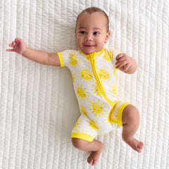 Child laying on a bed wearing a Sunshine Shorty Zippy