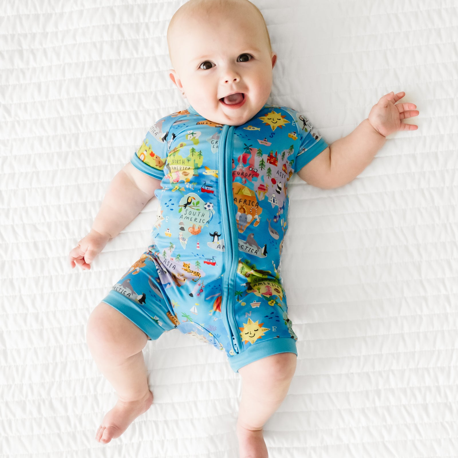 Child laying on a bed wearing an Around the World shorty zippy