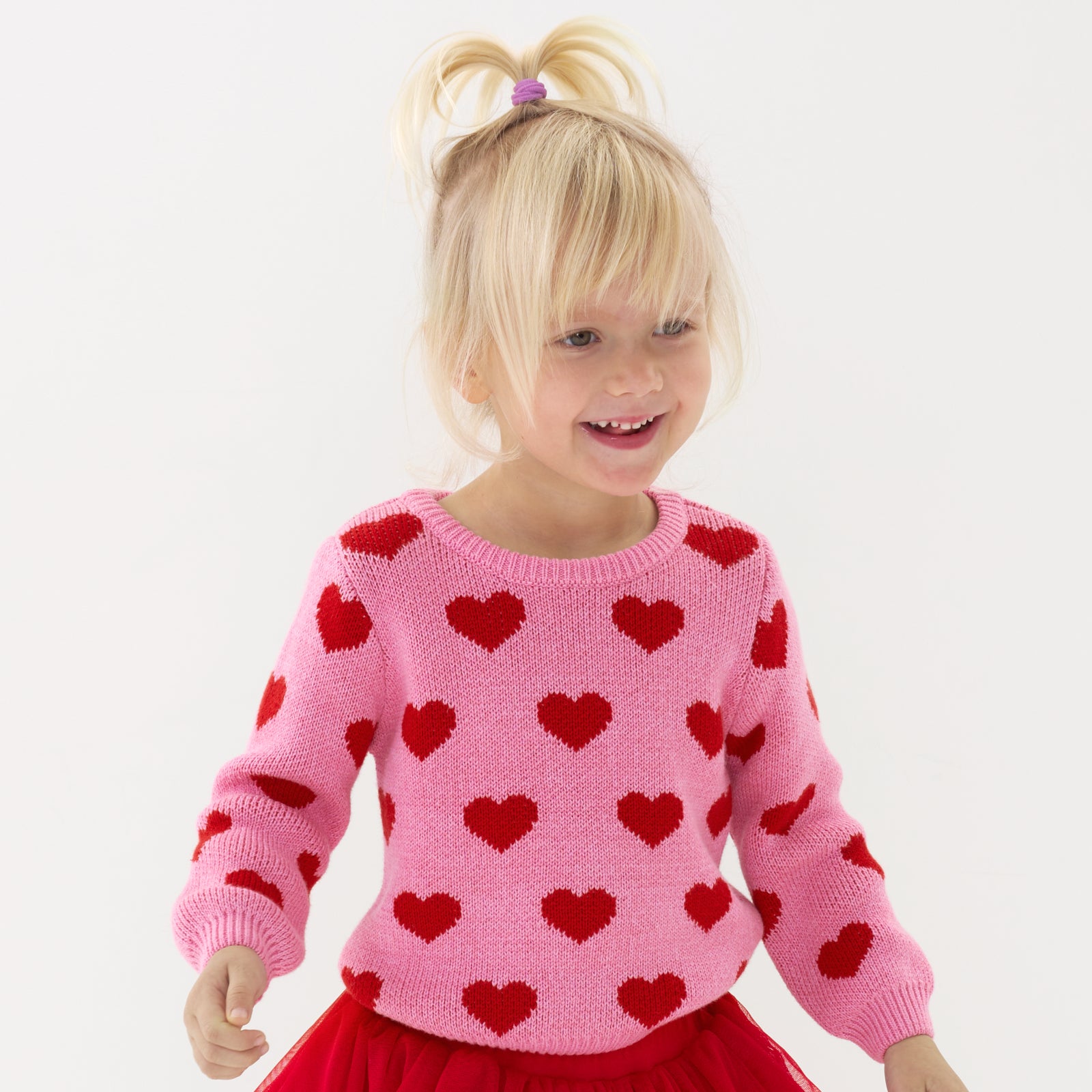 Close up image of a child wearing a Hearts knit sweater
