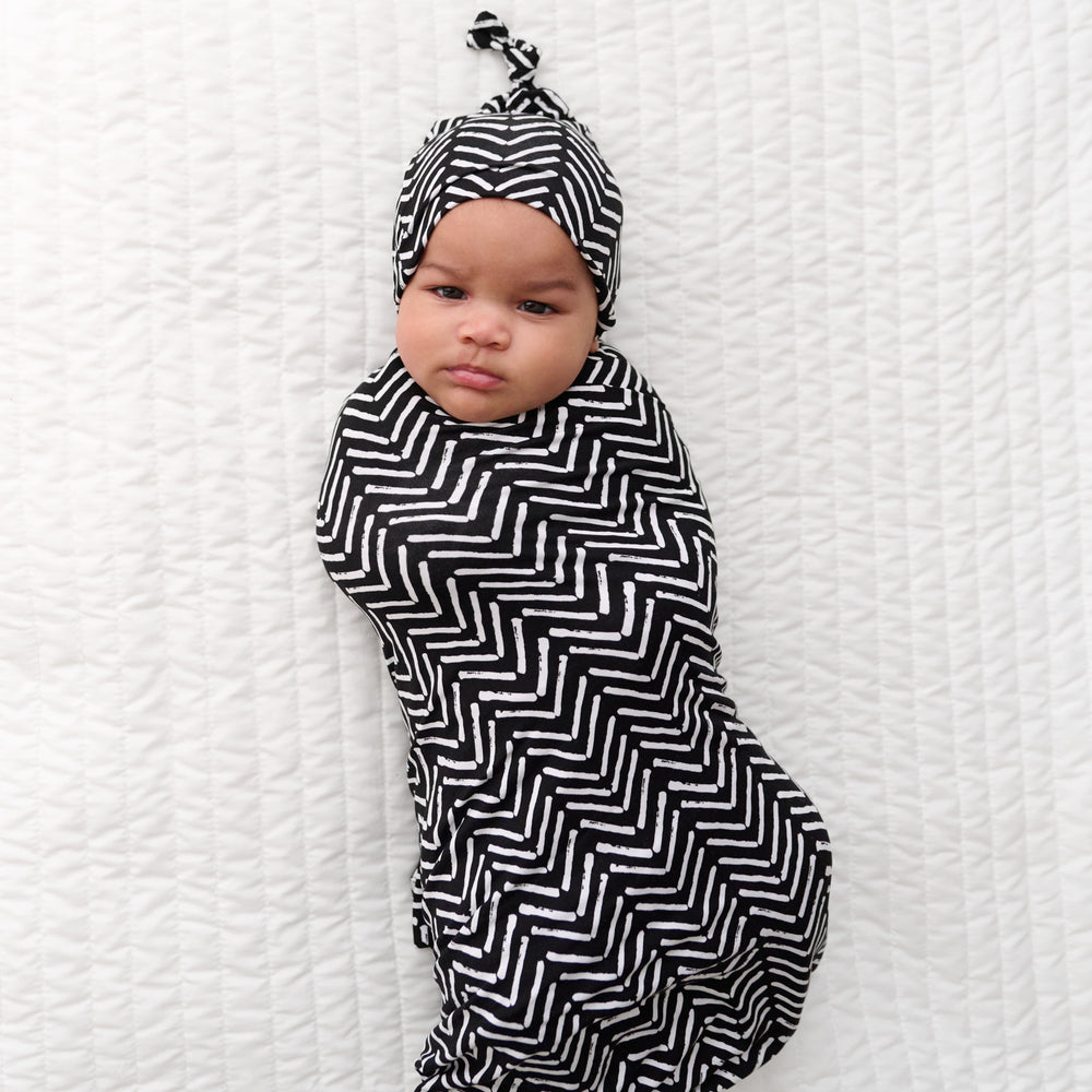 Child swaddled in a Monochrome Chevron swaddle and hat set