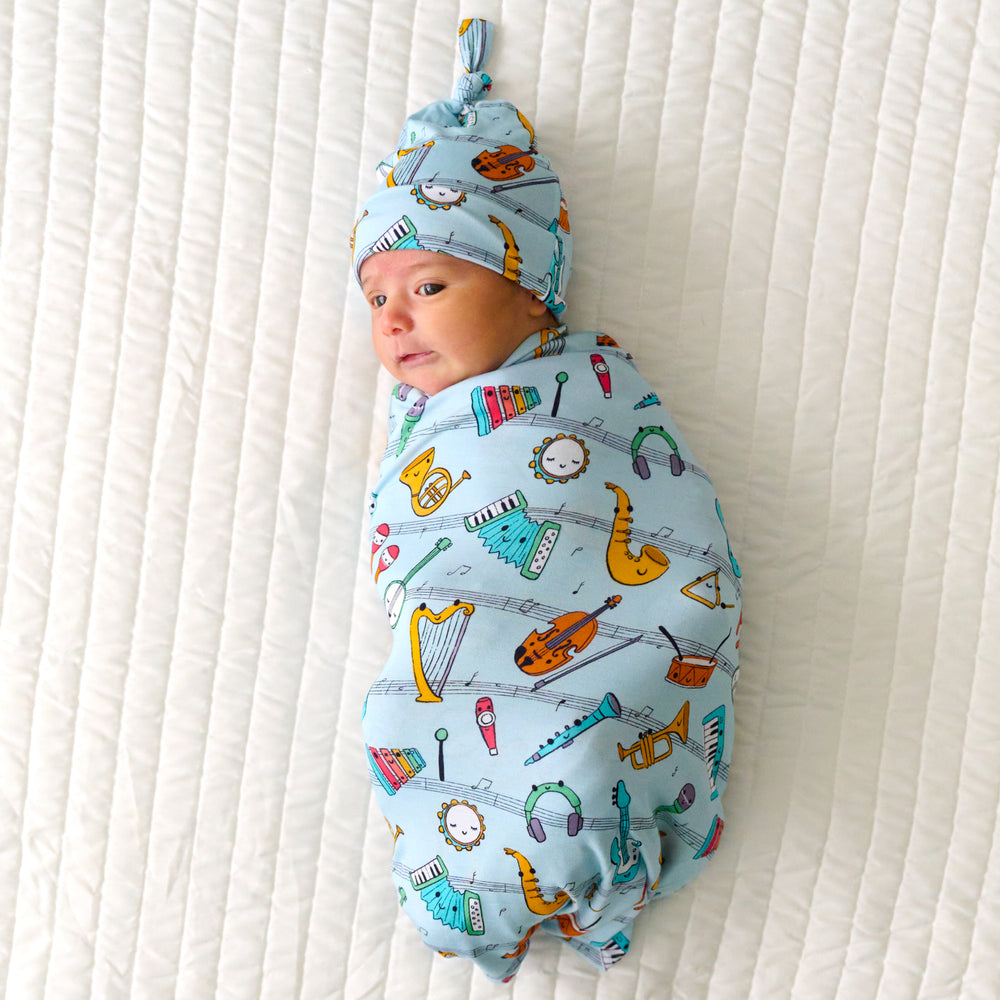 Infant swaddled in a Play Along swaddle and hat set